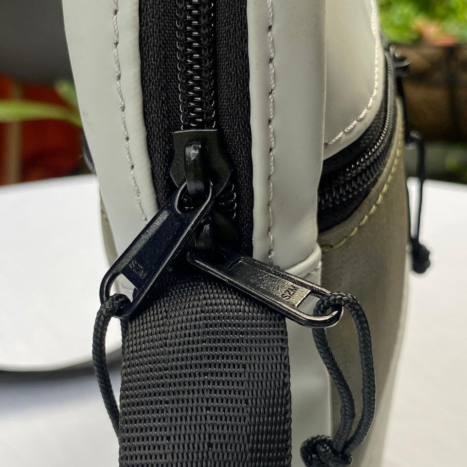 Close-up of a crossbody bag with a black zipper and strap